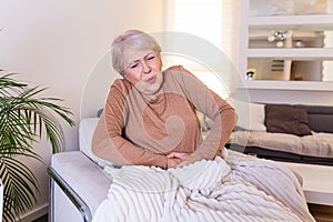 Old age, health problem and people concept - senior woman suffering from stomach ache at home. Senior woman suffering from stomach