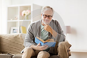 Senior man on sofa reading book at home