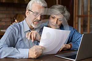 Old age married couple do paperwork engaged in reading document