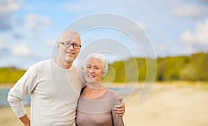 Happy senior couple hugging over beach background
