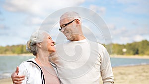 Happy senior couple hugging over beach background