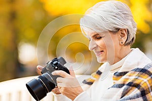 Senior woman with photo camera at autumn park