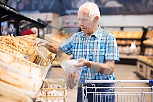 Elderly man buying bread and pastries in grocery section of the supermarket