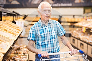 Old age senor examines bakery products in the grocery section of the supermarket