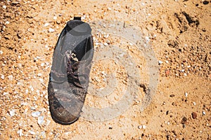 Old age worn shoe on the sand beach