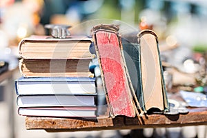 Old aged books at flea market. Vintage retro literature on wooden table outdoors. Street swap meet background