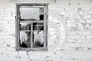 Old aged cracked white brick wall with broken window. Shattered dirty window glass and iron grates with black background