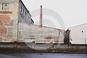 Old and aged factory and industrial building with ugly facade, smokestack and chimney
