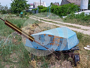 Old-aged rust-colored boat bottom at near village houses