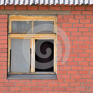 Old aged shed broken window glass, red bricks hut wall background, weathered grungy rusty dirty damaged wooden frame, textured