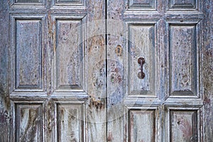 Old aged two-leaf door with metal decorations in natural wood