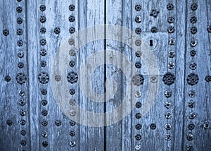 Old aged two-leaf door with metal decorations in natural wood