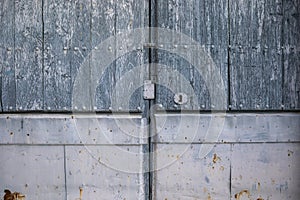 Old aged two-leaf door with metal decorations in natural wood