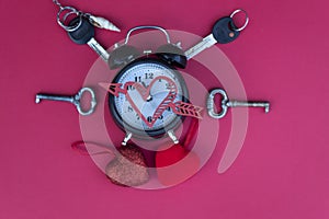 An old alarm clock with bells lies on a red background.