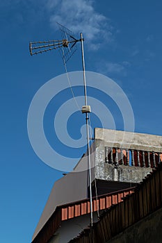 Old analog antenna for television stand tall between houses and buildings