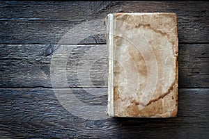 An old ancient book with empty cover on a wooden background.