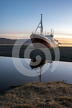 Old ancient, destroyed and abandoned norwegian whaling ship laying ashore in the westfjords of Iceland during sunset.