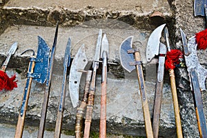 The old ancient medieval cold weapons, axes, olibards, knives, swords with wooden handles lick on the stone steps of the castle