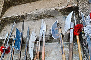 The old ancient medieval cold weapons, axes, olibards, knives, swords with wooden handles lick on the stone steps of the castle
