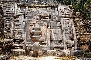 Old ancient stone Mayan pre-columbian civilization carved face and ornamen88t, Lamanai archeological site, Orange Walk District,