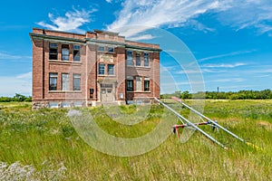 The old Aneroid Consolidated School in Aneroid, Saskatchewan with teeter totters in the foreground