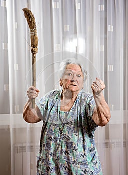 Old angry woman threatening with a broom