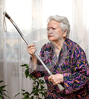 Old angry woman threatening with a cane