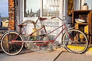 An old antique bicycle built for two in front of a country