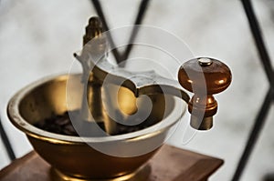 Old antique coffee grinder with coffee beans on a wooden windowsill.