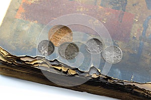 Old antique collectible coins and old book with shabby pages close-up isolated on white background