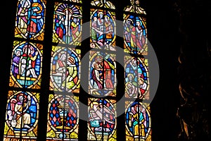 Old antique colorful stained glass windows in a darkened church, saints, bible scenes religious art decoration detail, closeup