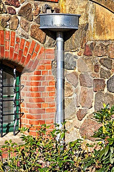 Old antique downpipe at a natural stone wall