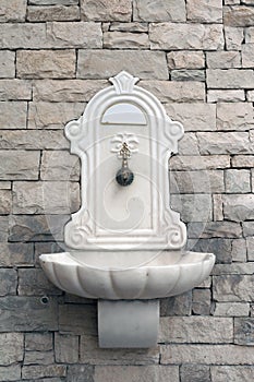 Old antique marble fountain on stone brick wall