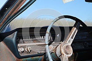 Old antique vintage retro rustic rusty dirty car steering wheel dashboard window outdoors in a field.