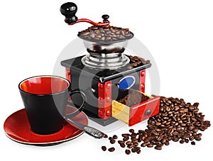 Old antique wooden black and red coffee grinder, cup, silver spoon and spilled coffee beans.