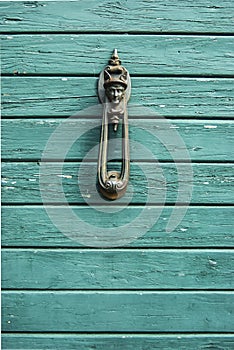 Old, antique wooden door with nostalgic door knocker with rogue motive