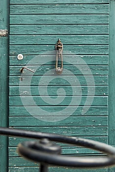 Old, antique wooden door with nostalgic door knocker with rogue motive in the foreground a wrought iron handrail photo