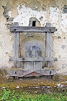 Old Antique wooden wine press in front of the old wall