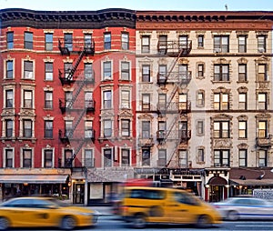 Old apartment buildings in the East Village neighborhood of New York City with taxis driving down the street