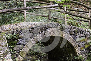 Old arch bridge over a mountain stream.