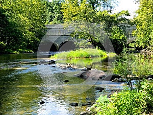 Old arch bridge over a small river at Gunpowder Park in Maryland on a warm summer day.