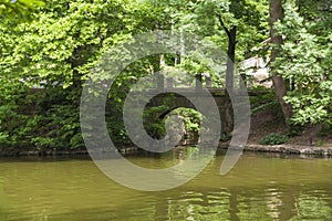 Old arched brick bridge over a pond in the Sofievka arboretum, Uman