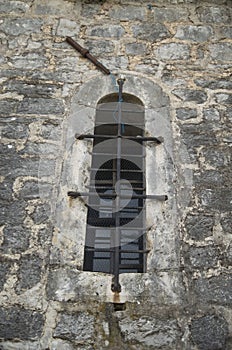Old arched window with metal grill on stone facade in Montenegro