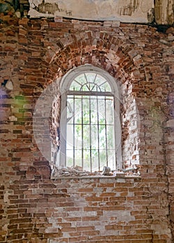 Old arched windows in an abandoned church, iron grilles in front of the windows, crumbling window sills and window sills