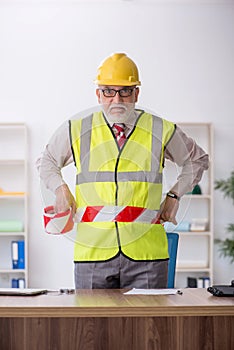 Old male architect holding caution tape