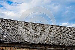 Old asbestos roof slates against blue sky.