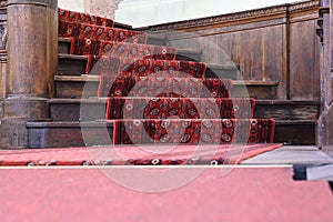 old ascending wooden stairs with ornate red carpet