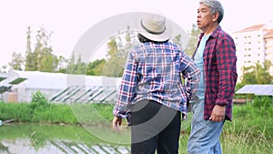 Old Asian couple farmers use tablets to adjust solar cells degree and check solar cell performance after rain and Dust and dirt