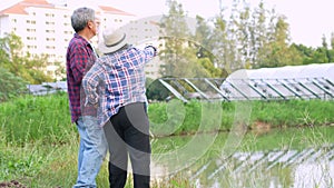 Old Asian couple farmers use tablets to adjust solar cells degree and check solar cell performance after rain and Dust and dirt