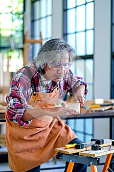 Old Asian craftsman act as measurement of wood in the room with wood pile and surround with glasses